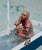 This oil on panel artwork depicts a solitary figure seated in a bathtub, her contemplative expression conveying a sense of...