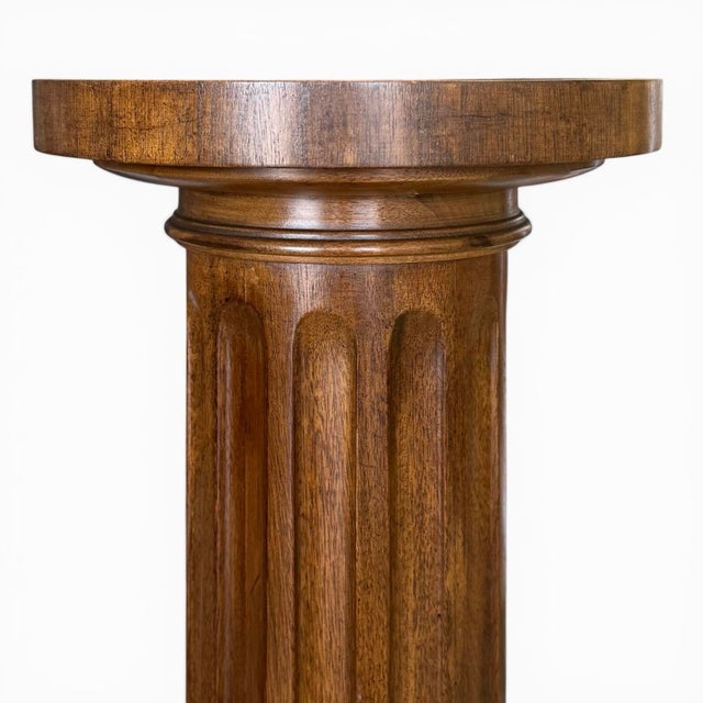 A finely crafted neoclassical pedestal in mahogany; an ebonized round top with raised galley of cross-banded mahogany...