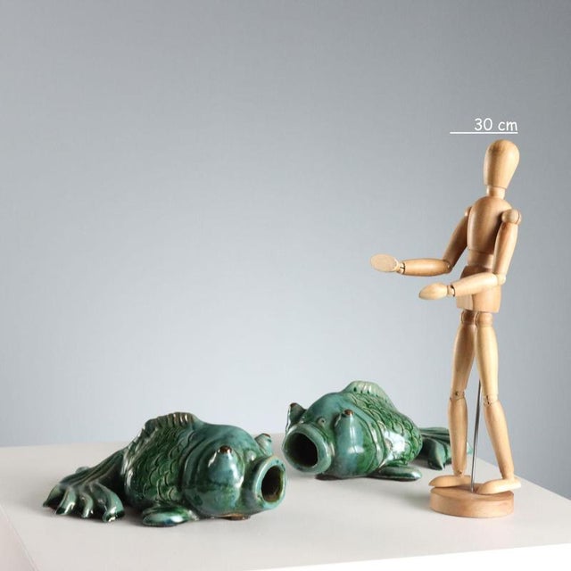 A pair of glazed ceramic sculptures in shades of green and blue depicting koi carp. They can also be used as wall-mounted...