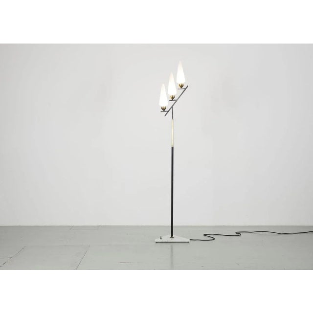 Floor lamp - Italy 1950s. The lamp has three opal glass tubes, a lacquered metal rod with brass elements and a triangular...
