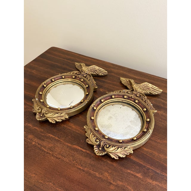 A gorgeous pair of Federal or Regency style small convex bullseye wall mirrors featuring an eagle with open wings and 13...