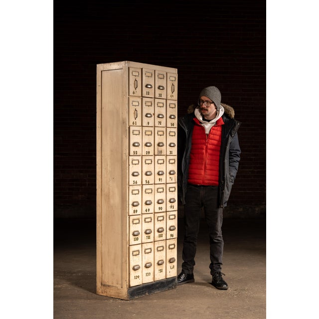 Tall, narrow ledger cabinet constructed in painted hardwood with a bank of twenty-eight small drawers arranged in a tight...