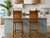 A beautiful pair of vintage coastal bar stools featuring bamboo frames with leather-wrapped accents, woven rattan...