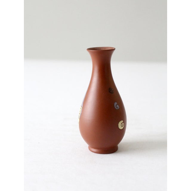 This is a vintage Vietnamese vase. The hand-painted redware vase has an art deco design in white, blue, and pale yellow...