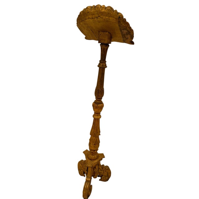 A carved giltwood music stand or lectern with a double carved shell shelf for music or a book. The turned columnar base...