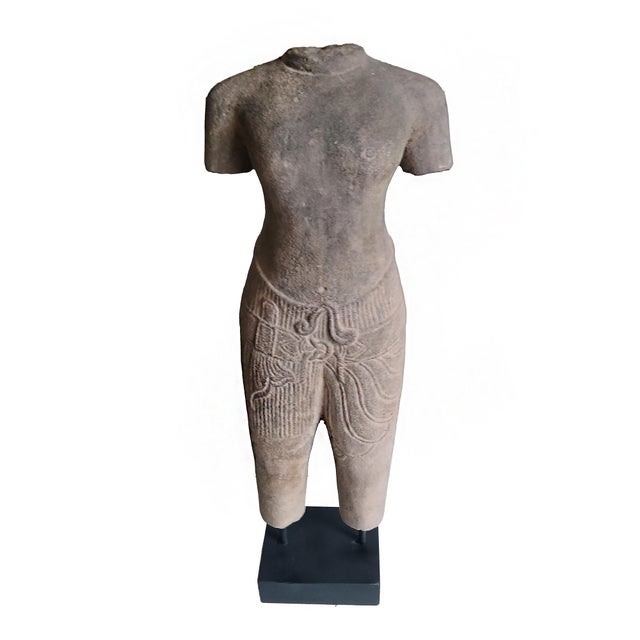A reclaimed sculpture of a male torso in traditional attire, hand-carved from a single piece of sandstone. Preserved in...