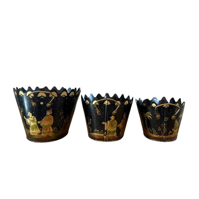 A lovely set of tole, nesting cachepots. Each features hand painted, Chinoiserie style figures and landscapes in rich...