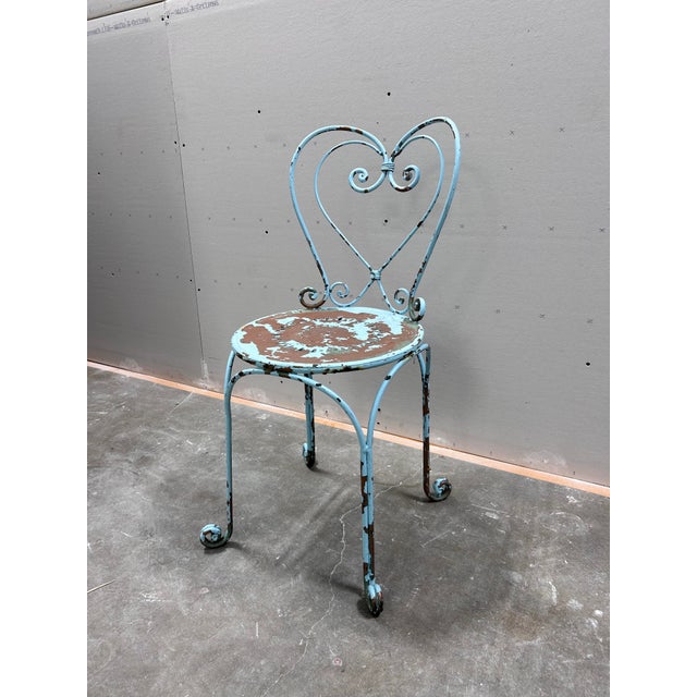A graceful pair of hand-forged French garden chairs, each with a heart-shaped back crowned in a classic ribbon-and-scroll...