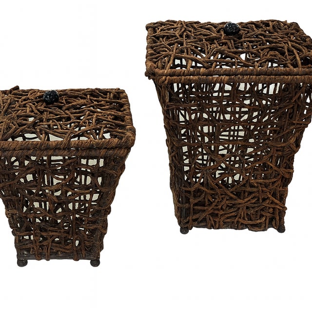 Charming pair of open-weave rattan baskets with matching lids, each topped with a small black metal bead finial. Crafted...