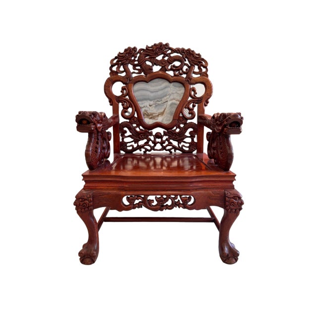 A striking antique Chinese armchair crafted from richly toned rosewood, featuring elaborate hand-carved detailing and...