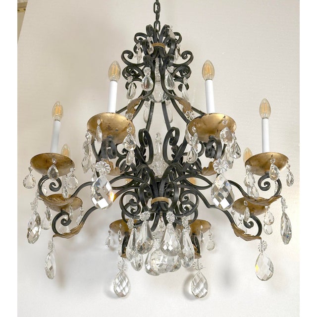 Spanish Revival style chandelier made of a black and gilt painted cast iron frame with eight arms and teardrop crystals....