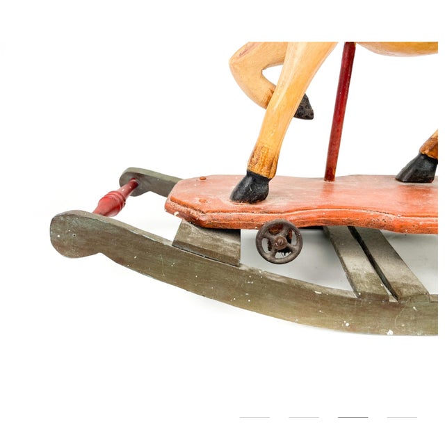A lovely medium-sized hand carved circa 1920s rocking horse painted beige with a leather saddle, brass stirrups and metal...