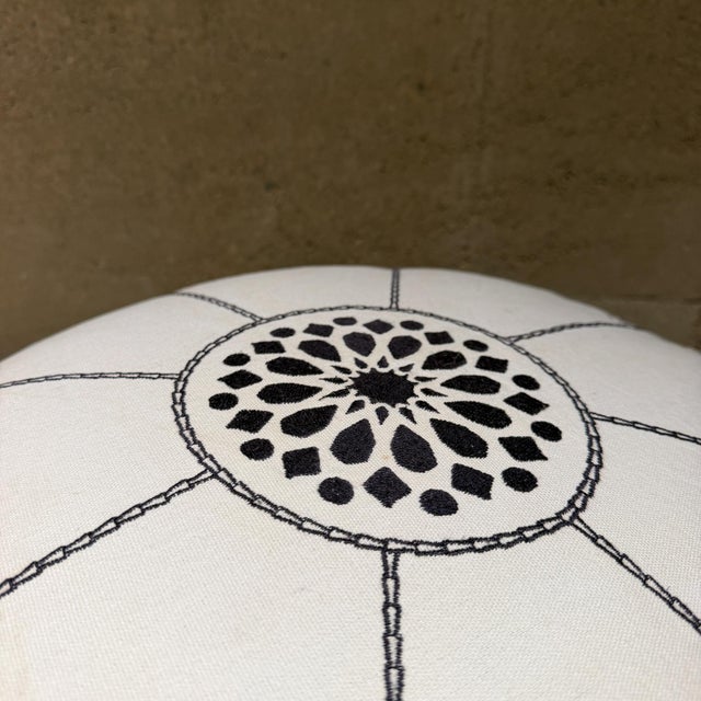 For your consideration, a white Moroccan fabric pouf featuring intricate dark grey geometric stitching and a central hand-...