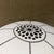 For your consideration, a white Moroccan fabric pouf featuring intricate dark grey geometric stitching and a central hand-...