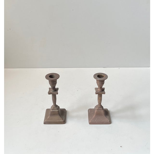 A pair of patinated bronze candlesticks for regular sized candles. Distinct functionalist styling with architectural...