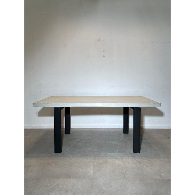 Sleek dining table by Xooon featuring a concrete-look top paired with sturdy matte black metal legs. The combination of...