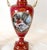 A fine pair of French Sèvres-style porcelain urns dating to circa 1880 Each urn features a rich ruby-red ground...