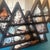 This unique display piece features a tiered, dark wooden frame crafted into geometric mountain peaks. Each compartment is...
