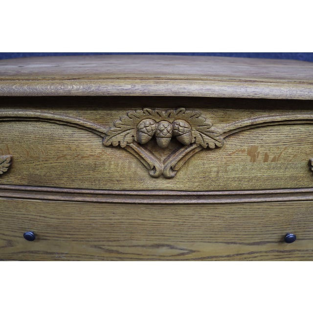 Solid oak four-drawer dresser by Oakwood Interiors featuring a warm honey oak finish and hand-carved acorn and oak leaf...