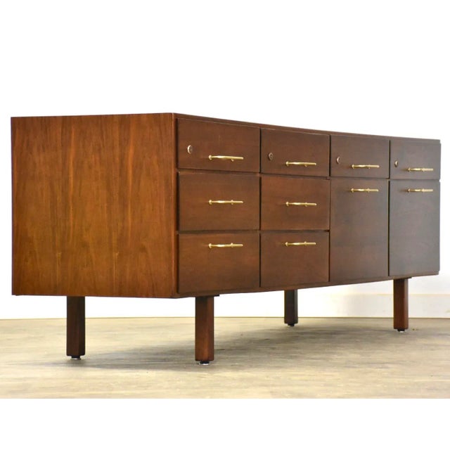 A mid century modern long credenza with brass drawer pulls designed by Jens Risom. Two drawers for hanging files....