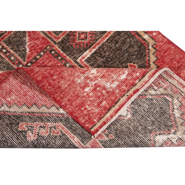 Beautiful Vintage Turkish hand-knotted Wool Runner with a red field. This rug has accents of brown and beige in a gorgeous...