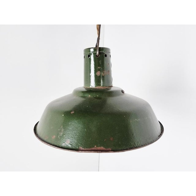 Vintage industrial pendant lights in dark green enamel. The lamps emit a soft light thanks to the white enamelled finish...