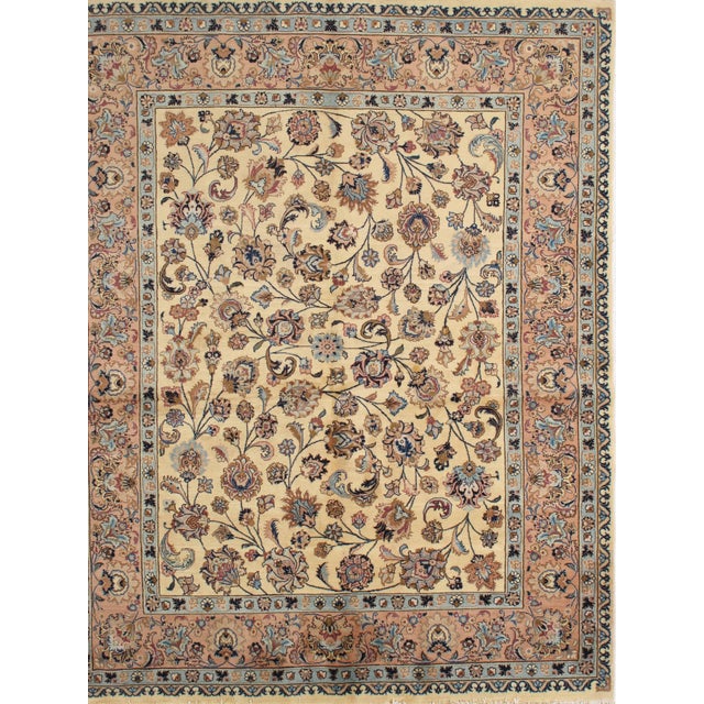 Antique hand-knotted Persian Mashad wool rug with a warm ivory field featuring a loose allover floral pattern of scrolling...