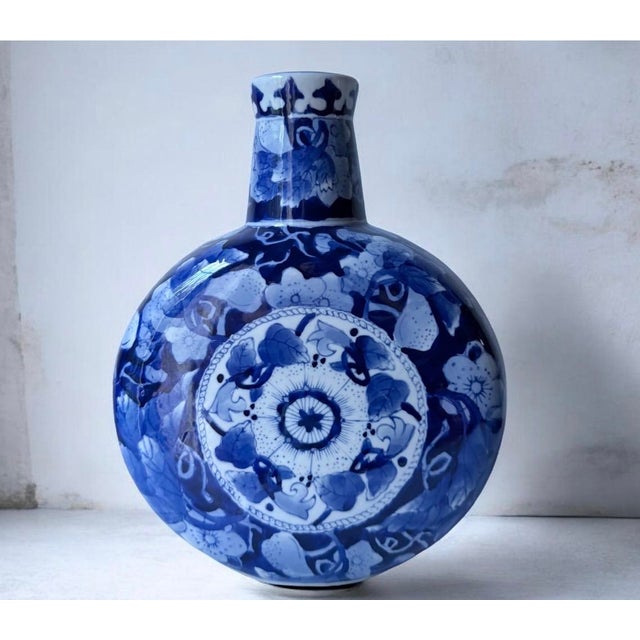 Elegant blue floral ceramic moon flask vase with traditional hand-painted design. The vivid blue and white pattern adds...
