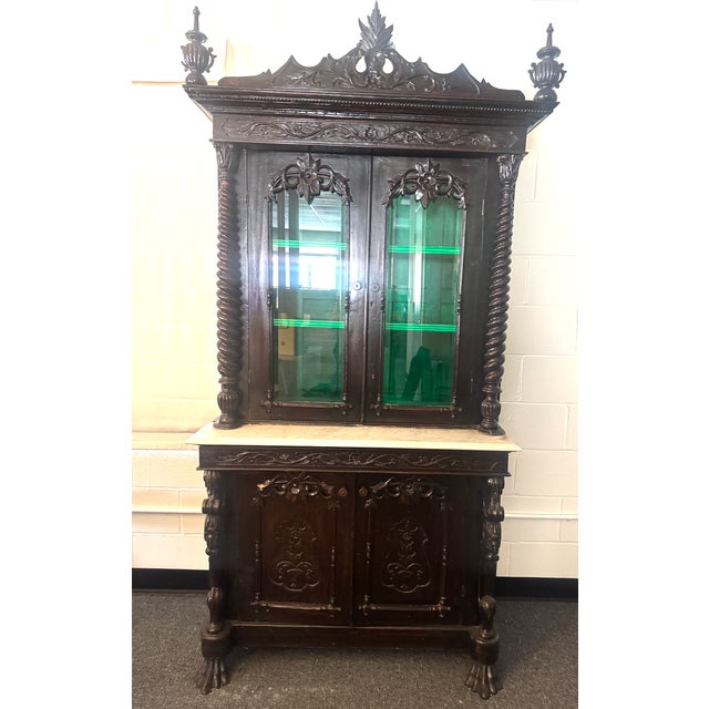 Wonderful ornately carved display cabinet, with some character marks and repair to the crest (see photos). Claw feet,...