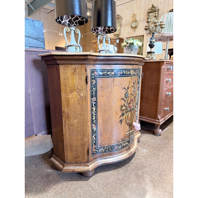 A charming vintage Italian console cabinet distinguished by its beautifully hand-painted floral decoration and graceful...