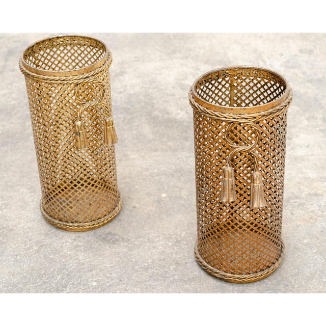 A lovely pair of 1950s umbrella stands in gold-tone metal. Their openwork design is adorned with twisted rope and small...