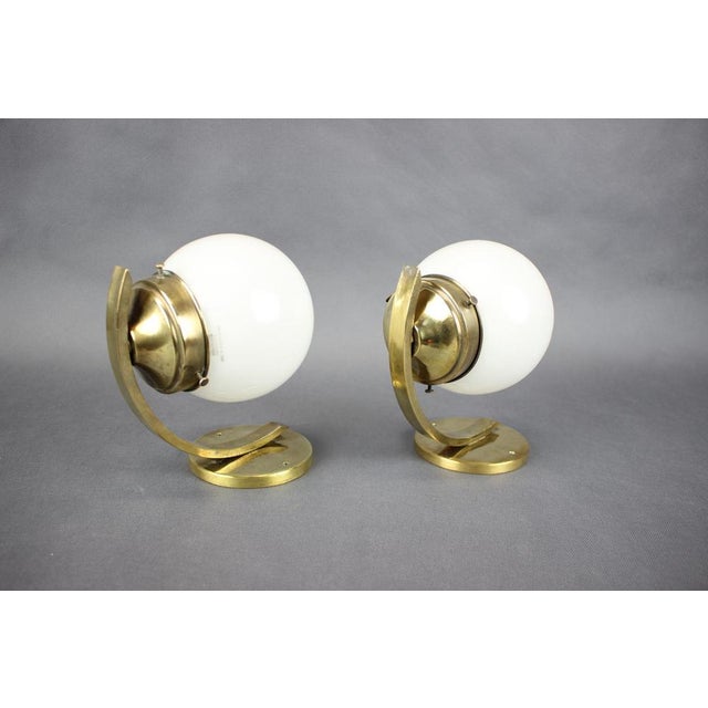 A refined pair of original Art Deco wall lamps dating from the 1930s, crafted in brass with opaline glass shades. These...