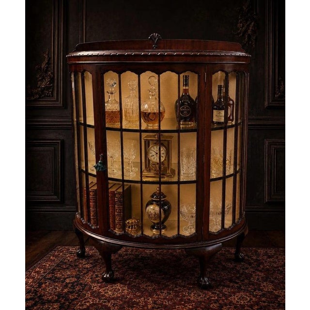 An elegant early 20th-century mahogany display cabinet of particularly attractive proportions, featuring a bowed glazed...
