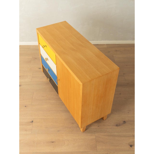 Classic 1950s chest of drawers. Ash veneer body with four Formica-coated drawers in yellow, cream, blue, and black, one...