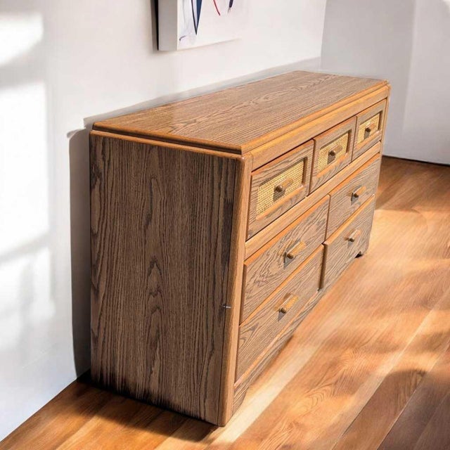 A long 1980s postmodern dresser with faux-oak laminate, clean rectilinear lines and woven-look insets across the upper...
