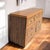 A long 1980s postmodern dresser with faux-oak laminate, clean rectilinear lines and woven-look insets across the upper...