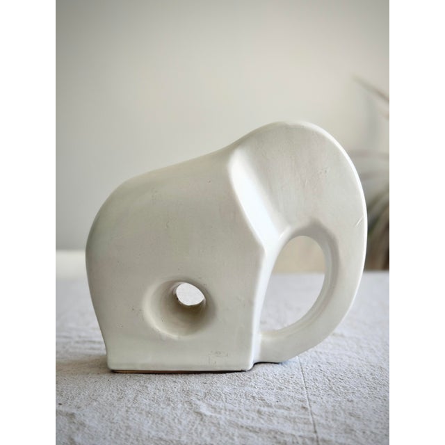 Vintage mid-century modern white ceramic elephant sculpture with a minimalist, sculptural form. The piece features smooth,...