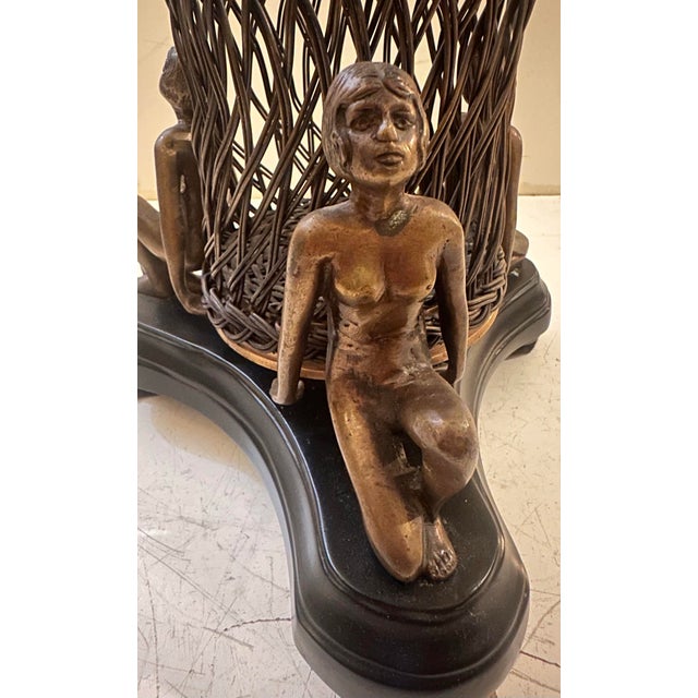 An Art Deco figural centerpiece basket, featuring a woven wire basket form flanked by three seated nude figures in a...