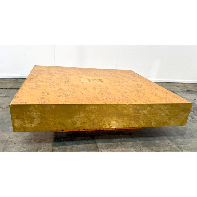 A bold Italian coffee table from the 1970s featuring a square burl wood top set within a substantial brass-clad frame. The...