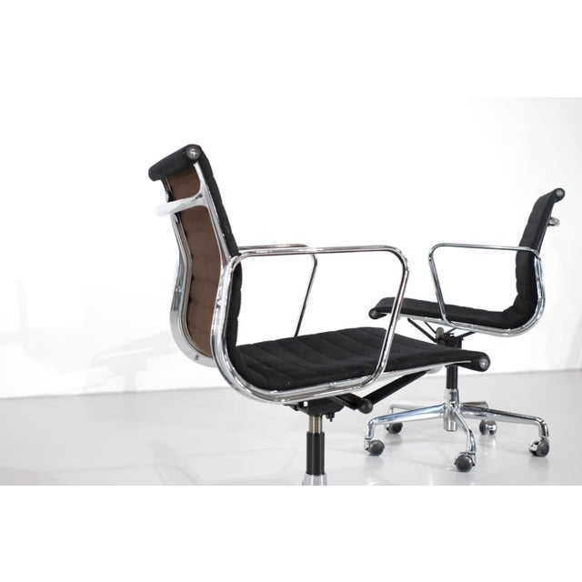 Set of four swivel chairs, model "ea 117", in black fabric, brown fabric backrest, and chrome frame on casters, height...