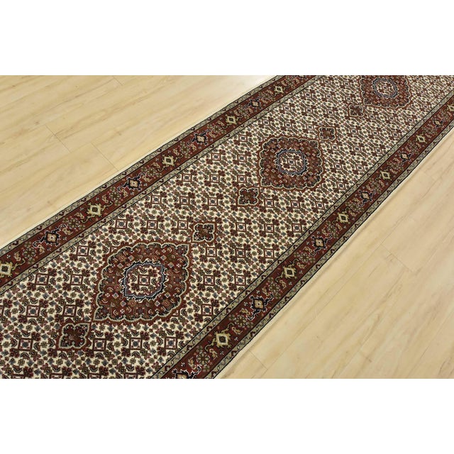A traditional Tabriz Mahi runner hand-knotted with fine wool on a cotton foundation. This intricately woven oriental rug...