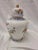 This lovely urn is from Andrea by Sadek. it features a white background with orange flowers and blue trip.