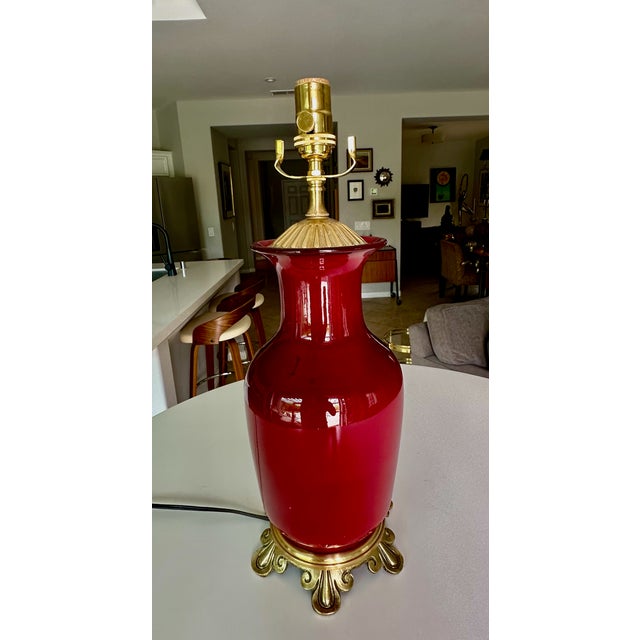 Single Chinese Asian Sang de Boeuf oxblood porcelain table lamp. The lamp vase is mounted on brass scrollwork base and...
