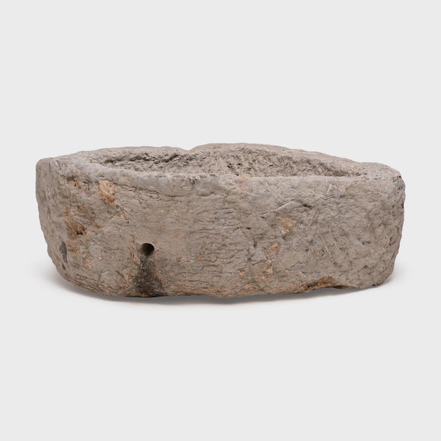 This large stone basin was carved by hand nearly two centuries ago, sculpted from solid limestone with irregular texture...