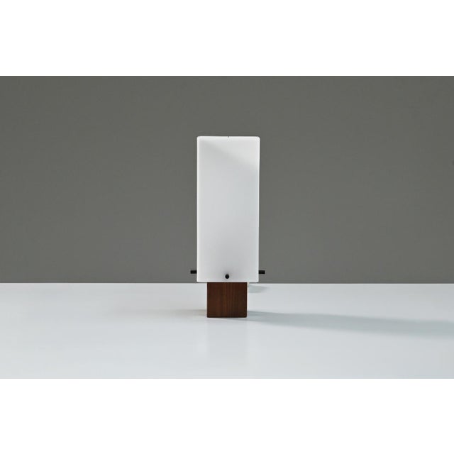 Vintage table lamp produced by Alfaplex Milano, 1960s Italy. The lamp features a solid teak wooden base combined with a...