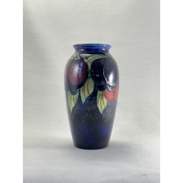 This exquisite 1920's Moorcroft miniature vase features the classic Wysteria and plum decoration, beautifully contrasted...