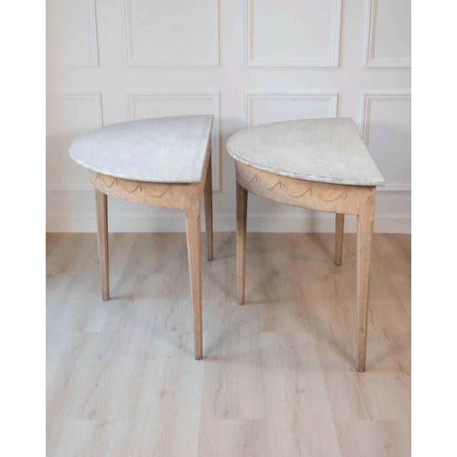 An elegant pair of Swedish demi-lune console tables in oak, dating to the mid-19th century. Each table features a graceful...