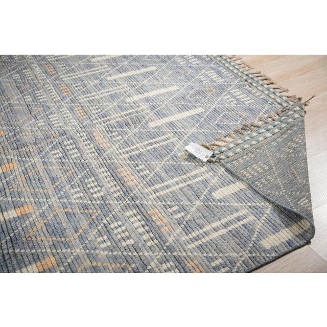 This hand knotted pile rug features a primary blue color palette and is crafted from durable wool. Designed in the style...