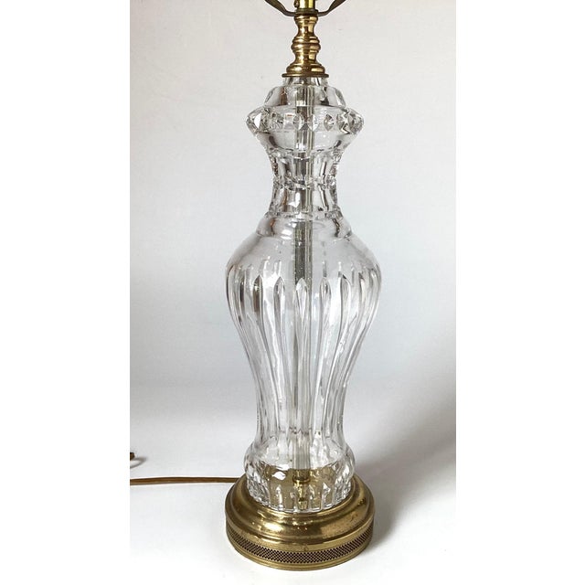 An elegant pair of cut crystal lamps with brass bases. The urn shape with vertical cuts on the body with a brass base....