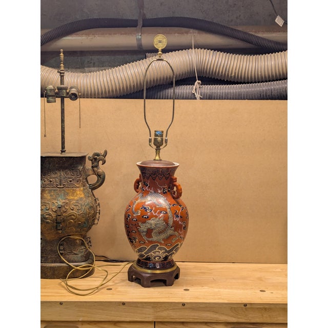 Ceramic cinnabar-colored with blue and white dragon details. Possibly originally a vase that was made into a lamp. Top and...